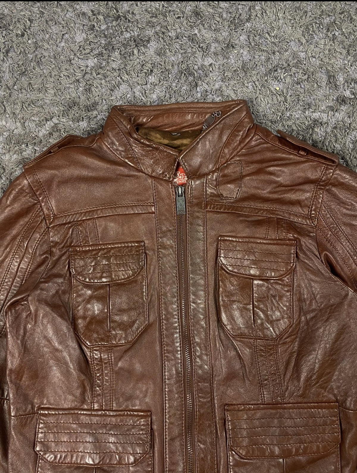 Close view of a patch pocket and the ribbed hem on the burgundy flight jacket