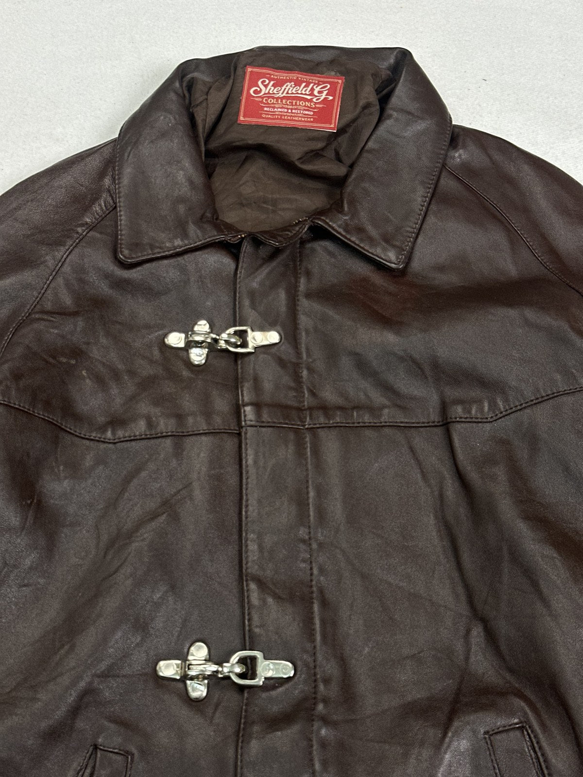 Collar and fireman clasp at the neck of the burgundy harrington
