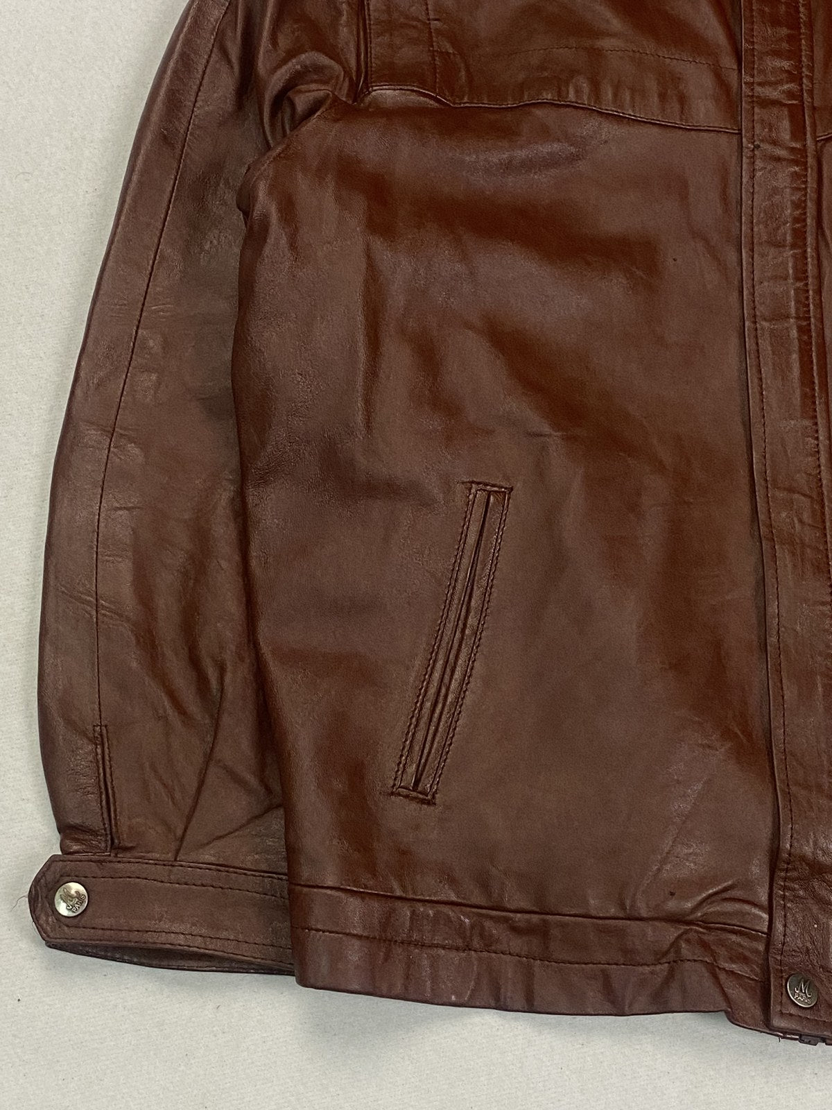 Close view of the snap hem tab and the burgundy leather grain