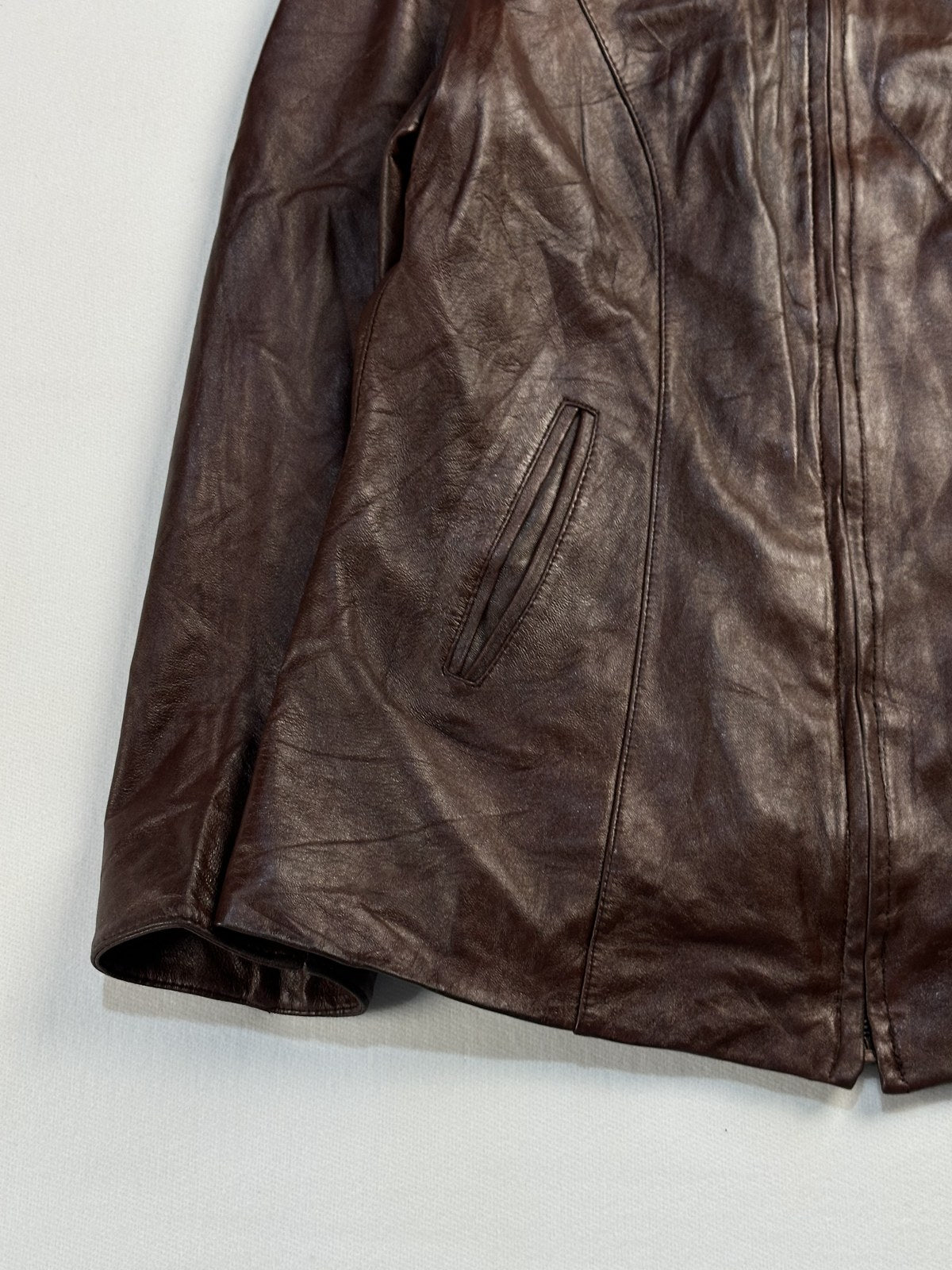 Close view of a slanted welt pocket and the burgundy leather grain