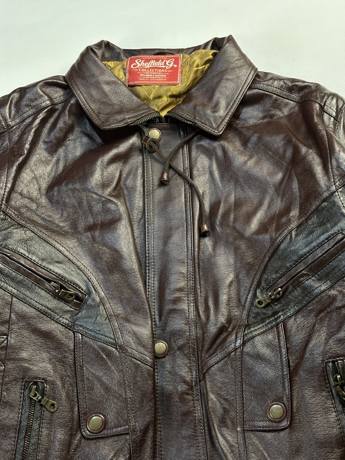 Throat drawcord at the collar of the burgundy leather harrington