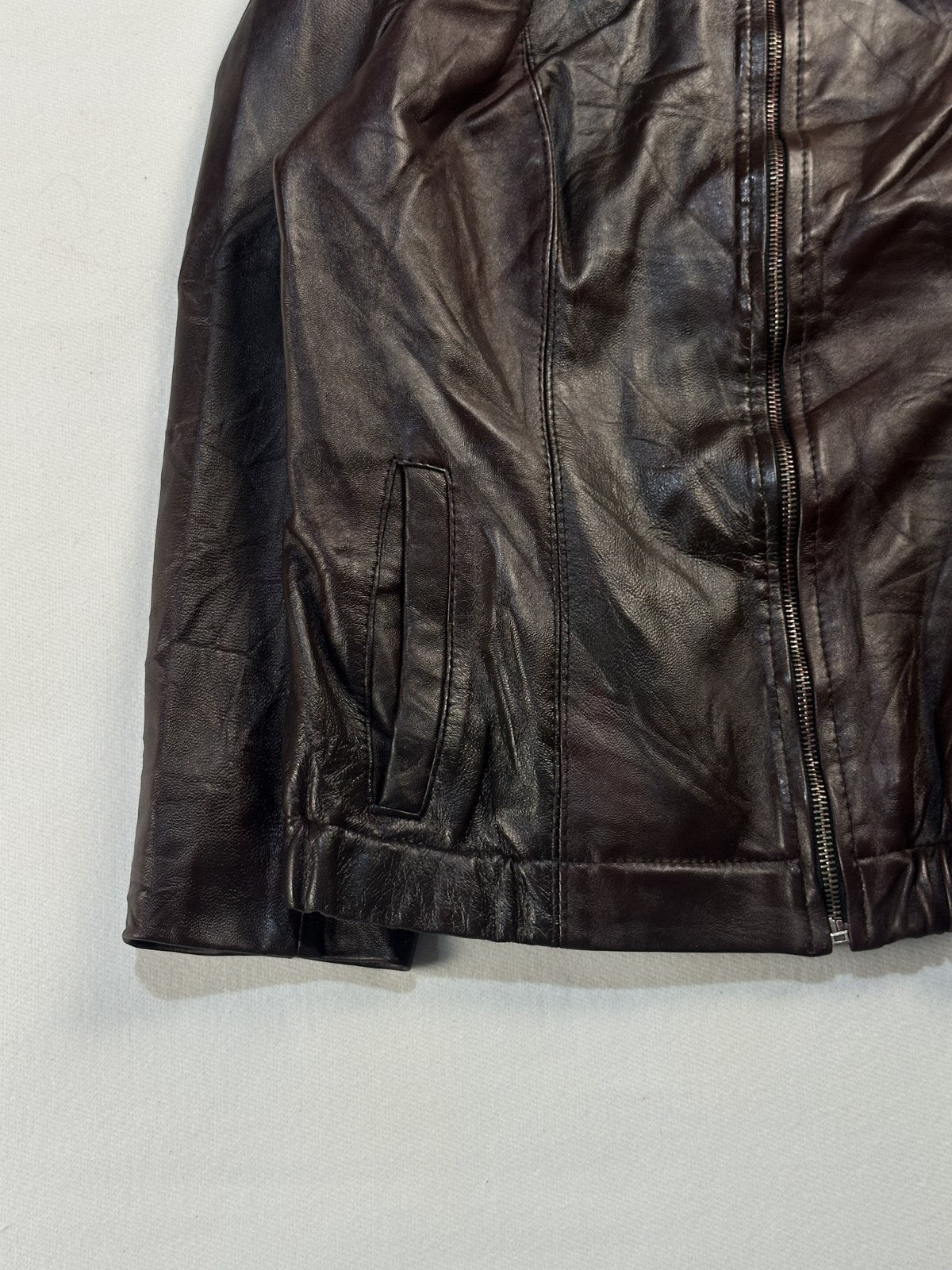 Close view of the leather grain and stitching on the burgundy jacket