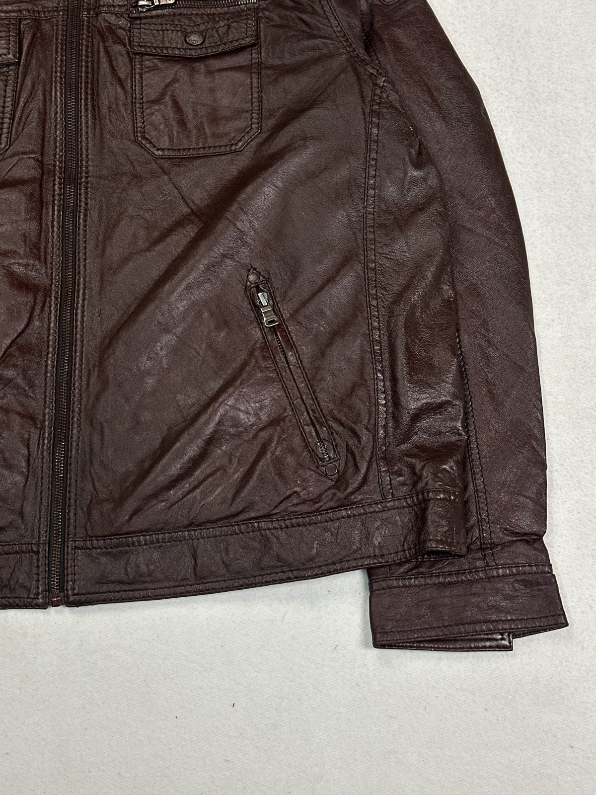 Close view of the leather grain and stitching on the burgundy jacket