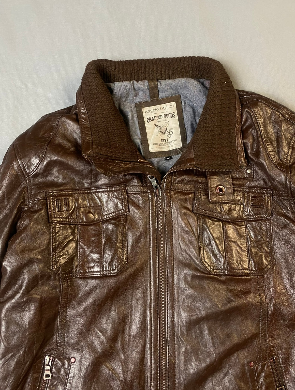 Close view of the knitted collar, chest flap pockets and front zip on this vintage brown jacket