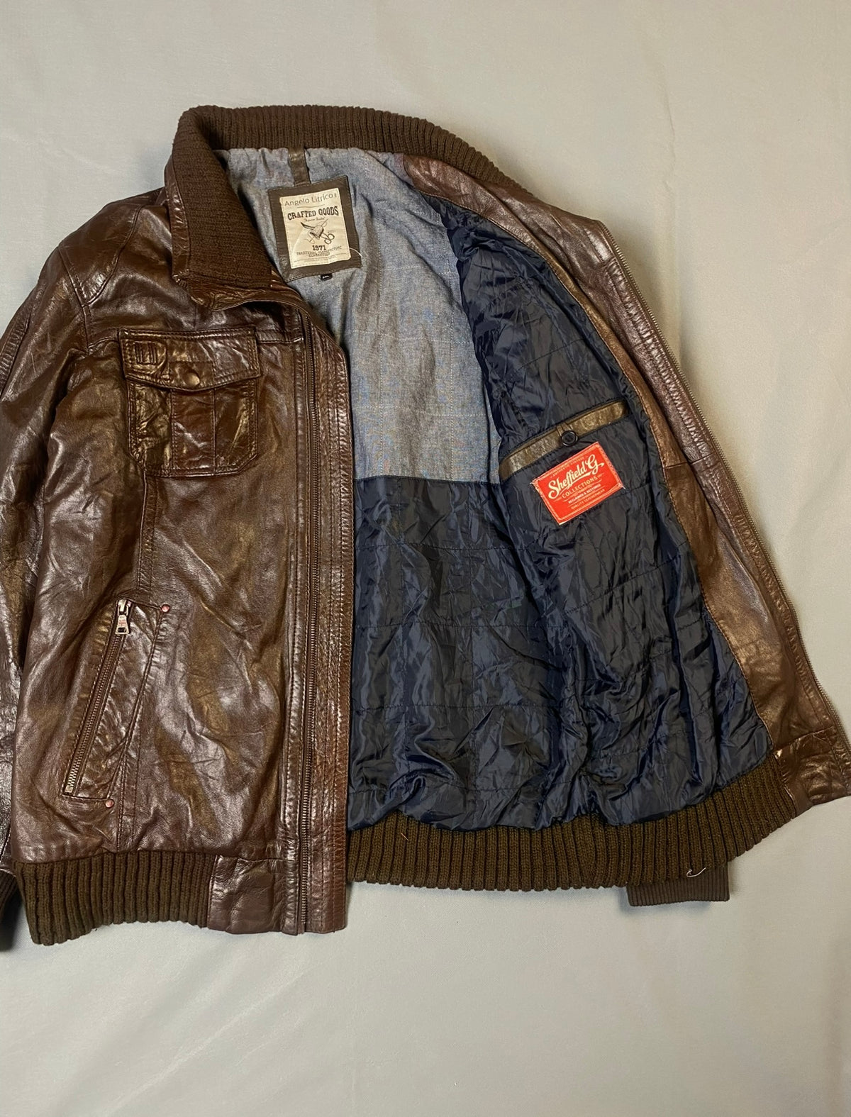 Blue lining inside the brown bomber jacket, held open to show the interior and inner label