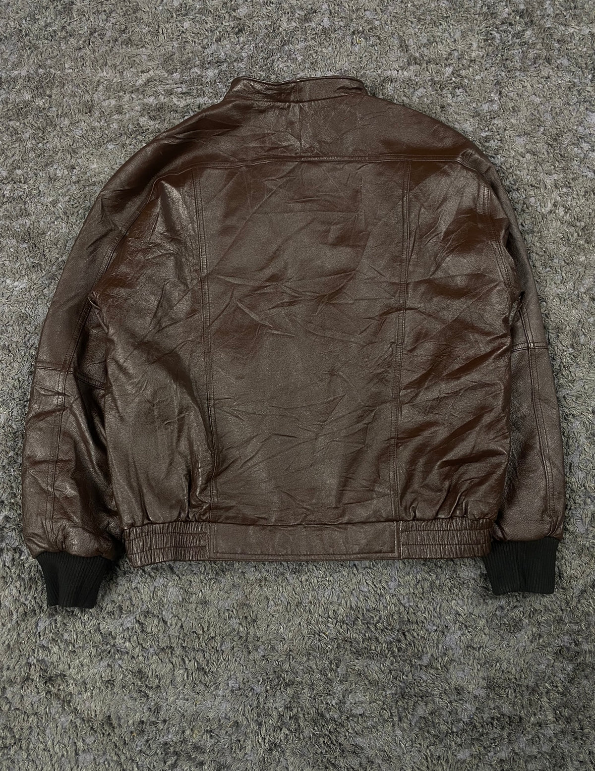 Back of the size L flight jacket laid flat, plain leather with a ribbed hem